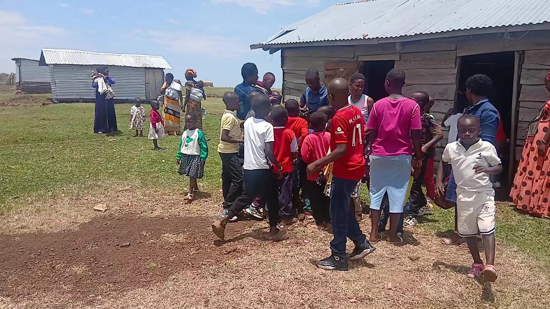 Children and adults mingle outside a timber hall after a gathering
