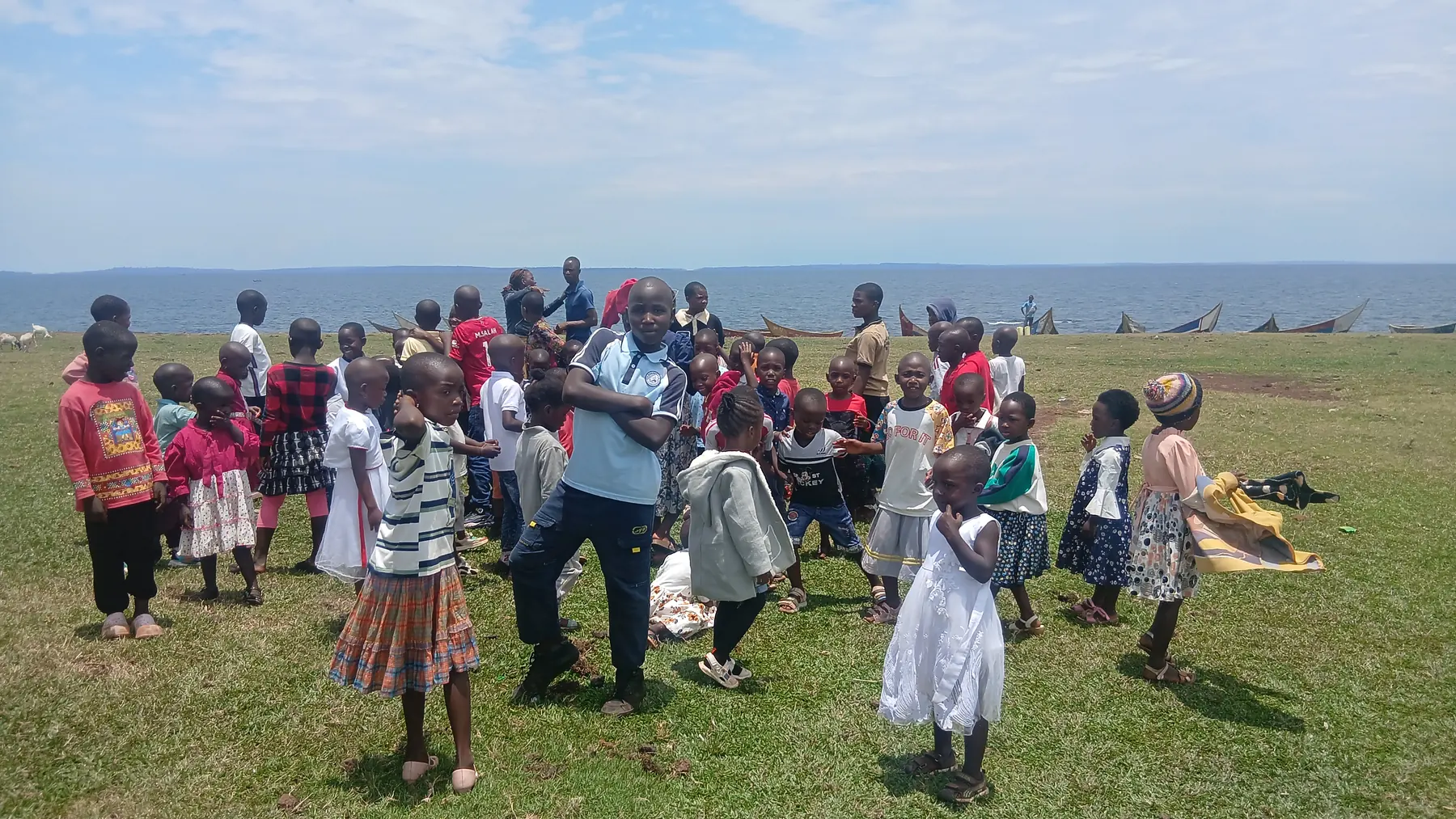 Children play together on open grass near the lakeshore